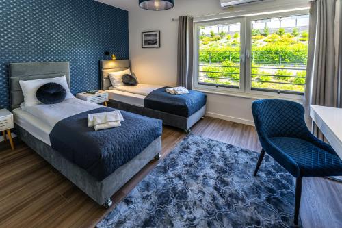 a bedroom with two beds and a chair and a window at Klif Resort Apartamenty in Mechelinki