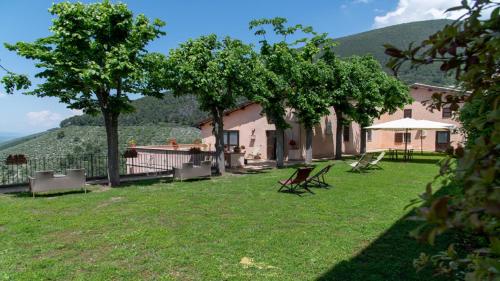 a house with a yard with chairs and trees at Relais Borgo Campello in Campello sul Clitunno
