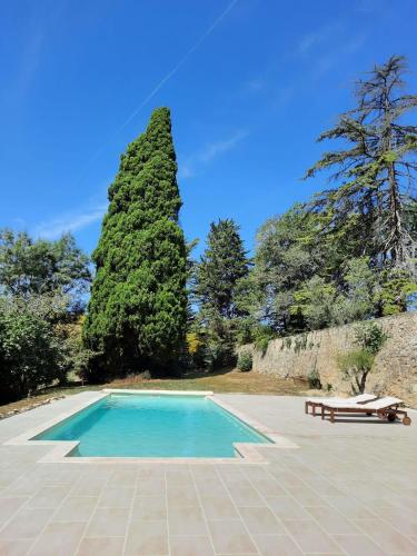 une piscine avec un banc et un arbre dans l'établissement Château de Gardès, à Castin