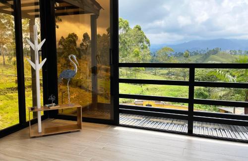 a room with a large window with a statue of a bird at Aguas Claras Luxury Hospedaje in Filandia