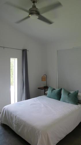 een slaapkamer met een wit bed en een plafondventilator bij Casa Catalina in Homestead