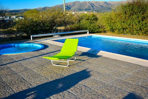 a green chair sitting next to a swimming pool at cabañas santa catalina in Villa Giardino