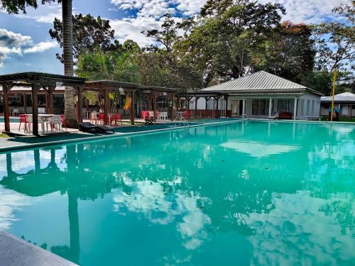 uma piscina com água azul em frente a uma casa em Hotel Cabañas River Park em Omoa