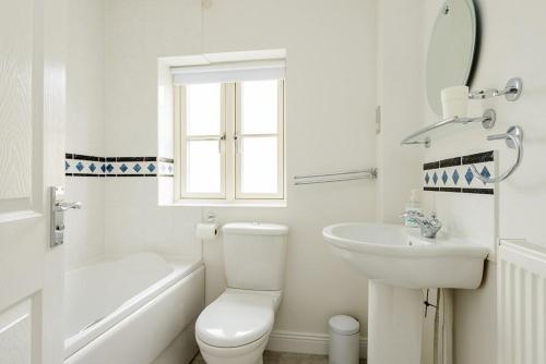 a white bathroom with a toilet and a sink at Gem Cottage in Chipping Campden