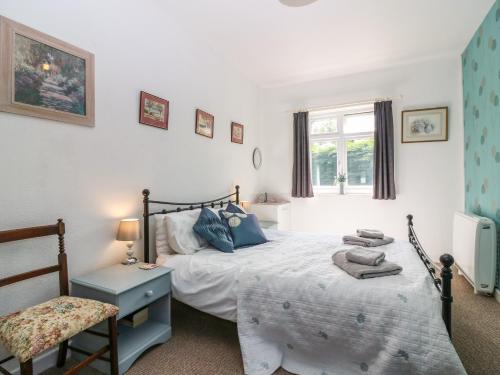 a bedroom with a bed and a chair and a window at Charlies Cottage in Duns