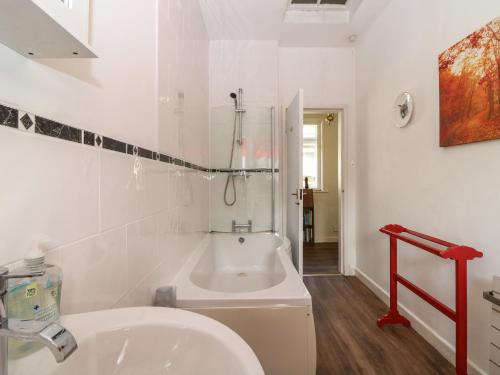 a white bathroom with a tub and a sink at Charlies Cottage in Duns