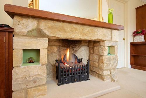 a stone fireplace with a fire in it at Badgers End in Chipping Campden