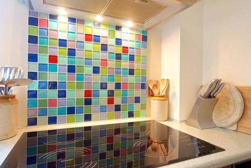 a kitchen with a colorful tiled wall at Badgers End in Chipping Campden