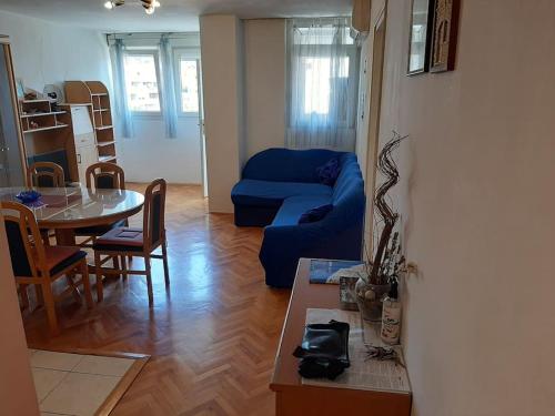 Apartment Mia في شيبينيك: غرفة معيشة مع أريكة زرقاء وطاولة