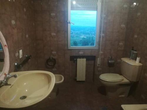 a bathroom with a sink and a toilet and a window at Casa rural a las afueras de Gijón in Gijón