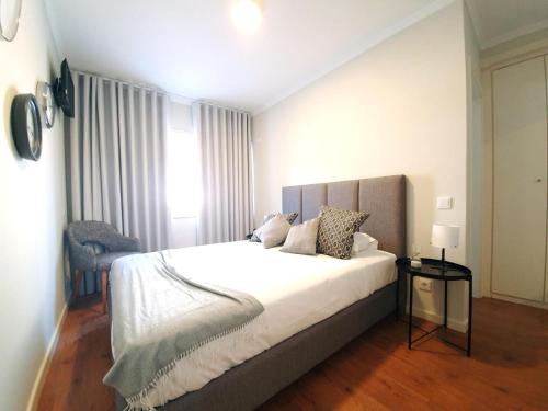 um quarto com uma grande cama branca e uma cadeira em Sonetos - Guest House no Porto