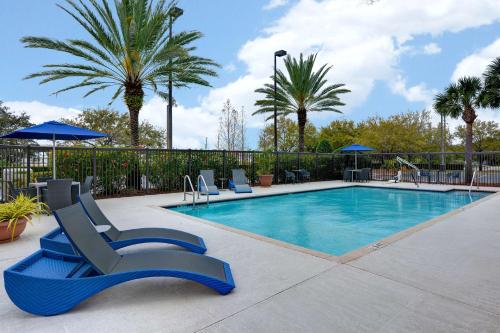 una piscina con sedie blu e palme di Hampton Inn & Suites Clearwater/St. Petersburg-Ulmerton Road a Clearwater