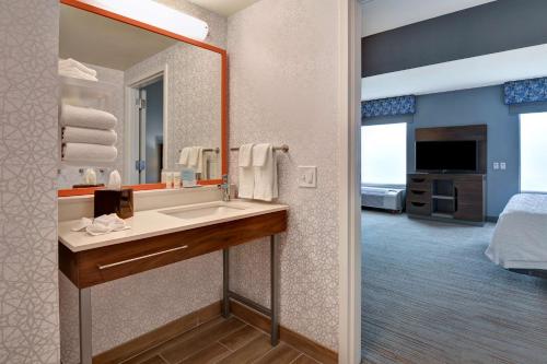 Hampton Inn & Suites Clearwater/St. Petersburg-Ulmerton Road في كليرووتر: حمام مع حوض ومرآة وسرير