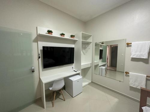 baño blanco con TV y espejo en River X House en Manaus