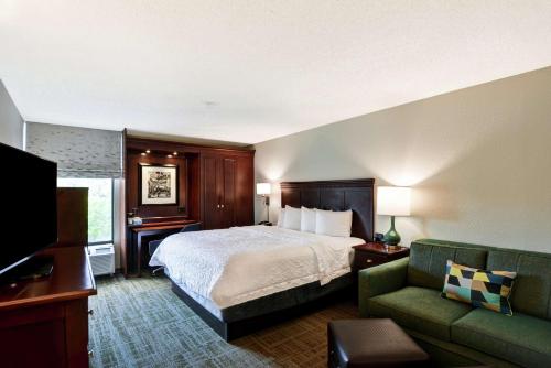 Hampton Inn Charlotte-Gastonia في غاستونيا: غرفه فندقيه بسرير واريكه