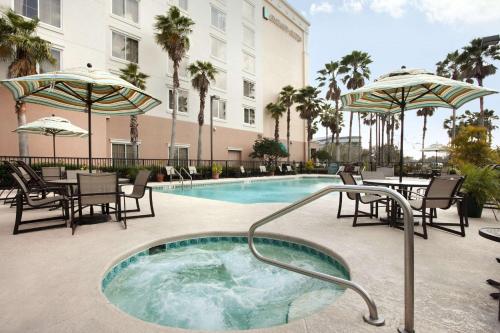 a hot tub with chairs and tables next to a building at Embassy Suites Orlando - Airport in Orlando