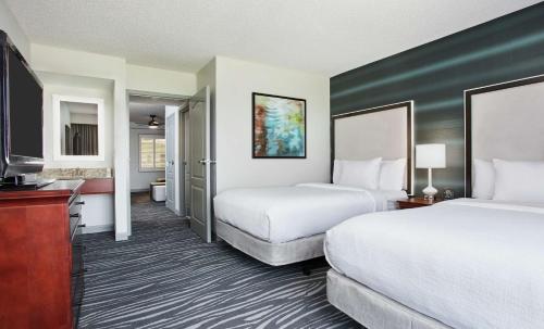 a hotel room with two beds and a television at Embassy Suites Orlando - Airport in Orlando