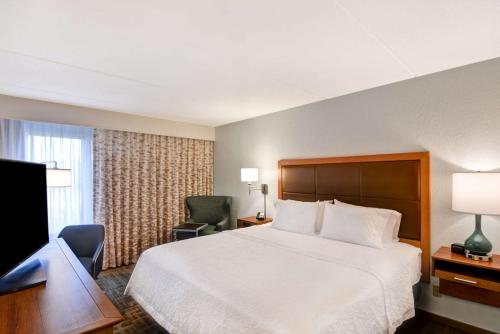 a hotel room with a bed and a desk and a television at Hampton Inn by Hilton Milford in Milford