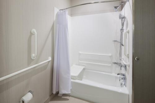 a bathroom with a shower and a white shower curtain at Courtyard by Marriott Houston North/Shenandoah in The Woodlands