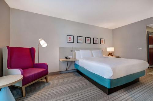 ein Schlafzimmer mit einem großen Bett und einem roten Stuhl in der Unterkunft Hilton Garden Inn Tampa Northwest/Oldsmar in Oldsmar