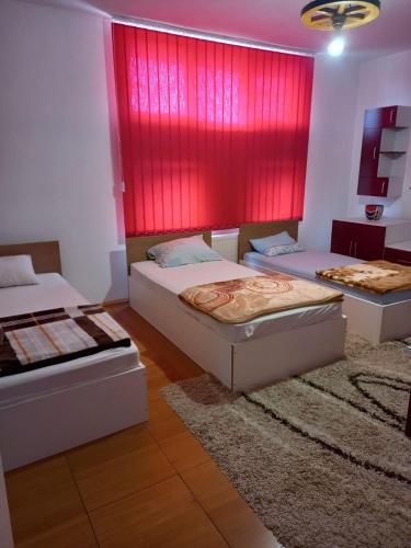 a bedroom with two beds and a red wall at Arthur 2 in Brčko