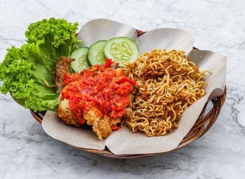 a bowl of food with noodles and vegetables on a table at Sabai Sabai Guesthouse in Bayan Lepas in Bayan Lepas
