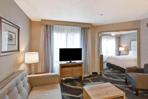 a hotel room with a bed and a flat screen tv at Homewood Suites by Hilton Windsor Locks Hartford in Windsor Locks