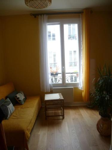 un salon avec un canapé et une fenêtre dans l'établissement Cocon cosy & calme / Montmartre, à Paris