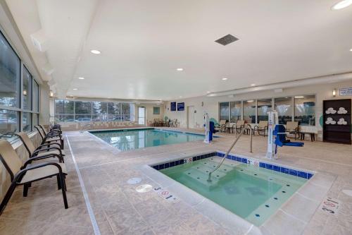 a large swimming pool in a building with chairs and tables at Hampton Inn & Suites Seattle/Federal Way in Federal Way