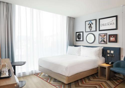 a bedroom with a white bed and a blue chair at Hampton By Hilton Dublin City Centre in Dublin