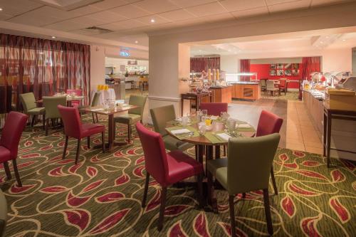 a dining room with tables and red chairs at Hilton Leicester Hotel in Leicester