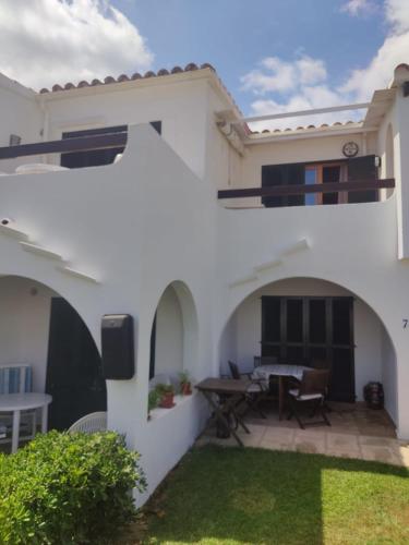 a white house with a patio with a table at Biniplaya - Apartamento reformado al lado de la playa in Arenal d'en Castell