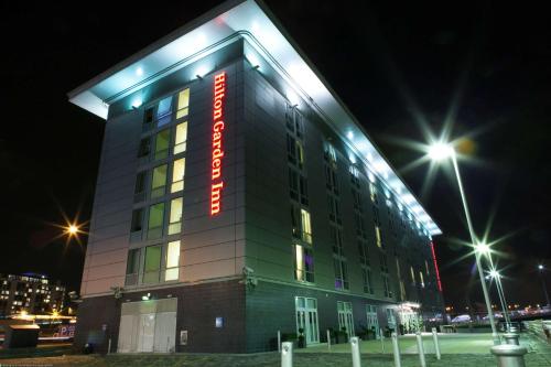 un bâtiment avec un panneau de néon sur lui la nuit dans l'établissement Hilton Garden Inn Glasgow City Centre, à Glasgow