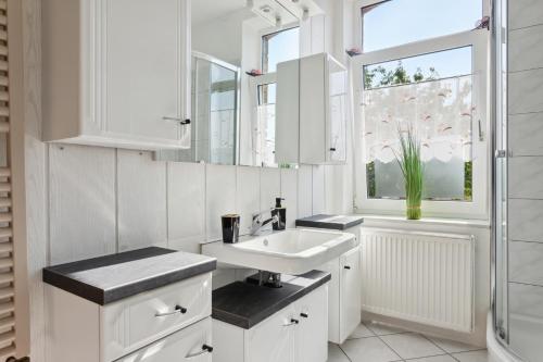 een witte badkamer met een wastafel en een raam bij Schönes Ferien-Appartement für bis zu 6 Personen in Halberstadt