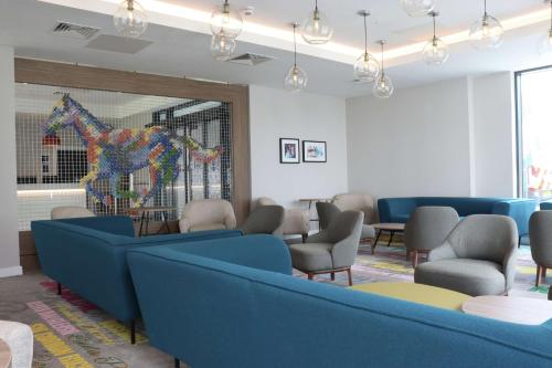 a waiting room with blue chairs and a horse statue at Hampton By Hilton Hamilton Park in Hamilton