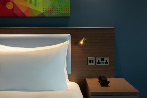 a bed with a white pillow and a wooden head board at Hampton By Hilton Hamilton Park in Hamilton