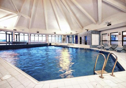 Doubletree By Hilton Glasgow Westerwood Spa & Golf Resort في كومبيرنولد: مسبح كبير في مبنى به نوافذ