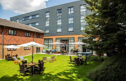 a hotel with tables and chairs in front of a building at Hilton Garden Inn Abingdon Oxford in Abingdon
