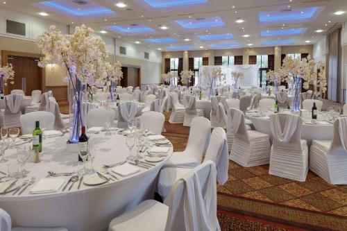 a banquet hall with white tables and white chairs at Glasgow Westerwood Hotel, Spa & Golf Resort in Cumbernauld