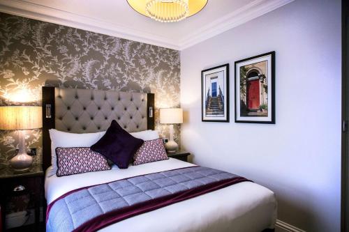 a bedroom with a king sized bed with purple pillows at DoubleTree by Hilton Cheltenham-Cotswolds in Cheltenham
