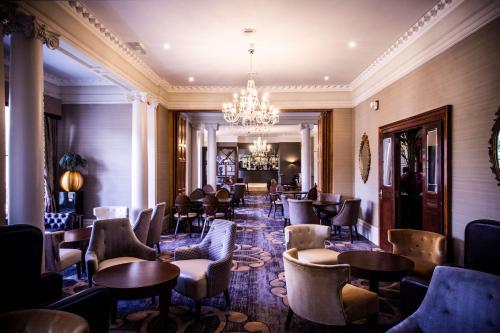 a restaurant with chairs and tables and a chandelier at DoubleTree by Hilton Cheltenham in Cheltenham