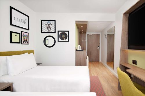 a hotel room with a bed and a flat screen tv at Hampton by Hilton High Wycombe in High Wycombe
