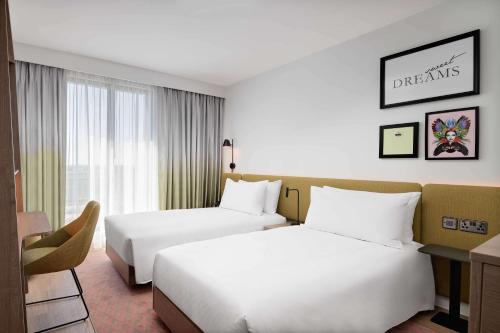 a hotel room with two beds and a desk at Hampton by Hilton High Wycombe in High Wycombe