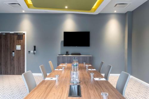 a conference room with a long table and a flat screen tv at Hampton by Hilton High Wycombe in High Wycombe