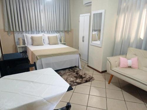 um quarto de hotel com uma cama e um sofá em Pousada Estrela Mares em Guarda do Embaú