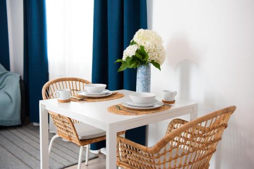 una mesa blanca con sillas y un jarrón con flores en Apartamenty Emilia en Gniezno