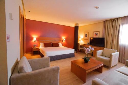 um quarto de hotel com uma cama e uma sala de estar em Hotel Reston Valdemoro em Valdemoro