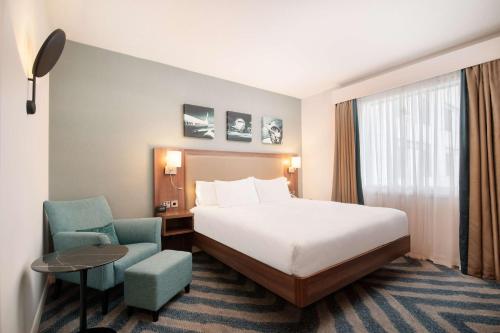 a hotel room with a bed and a chair at Hilton Garden Inn London Heathrow Airport in Hillingdon
