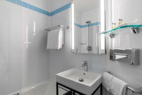a white bathroom with a sink and a mirror at Hilton Garden Inn London Heathrow Airport in Hillingdon