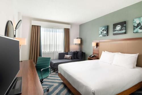 a hotel room with a bed and a chair at Hilton Garden Inn London Heathrow Airport in Hillingdon